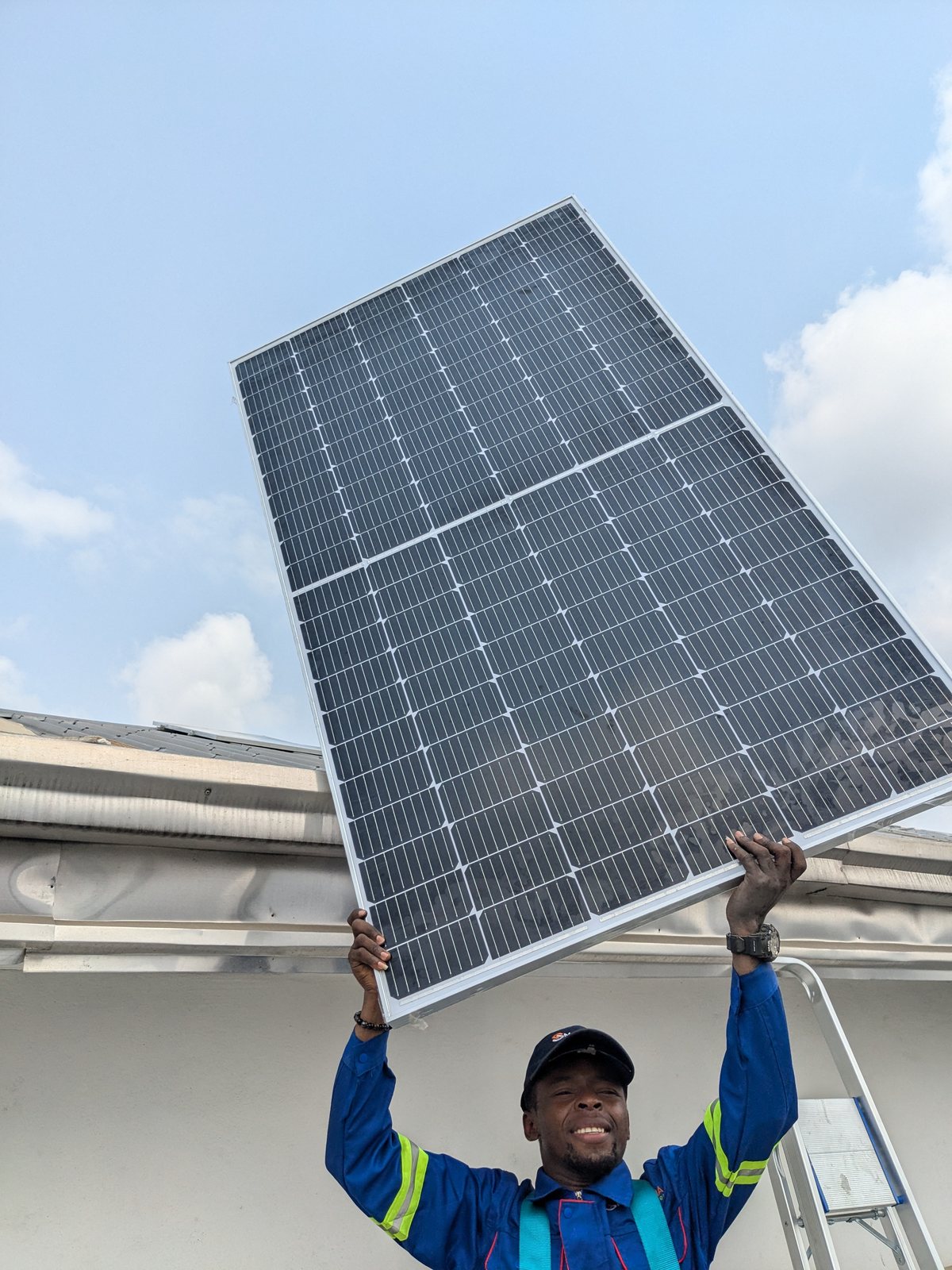 SmartSana technician raising a solar panel overhead, STIHL Douala