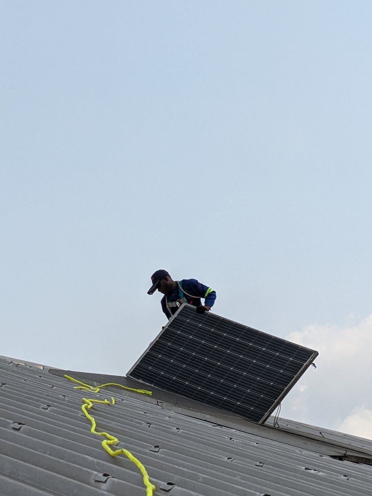 SmartSana technician hoisting a solar panel onto the STIHL roof, Douala